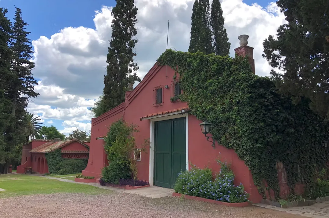 An ivy-covered outbuilding at Estancia La Loma with tall green double doors and cypresses behind it