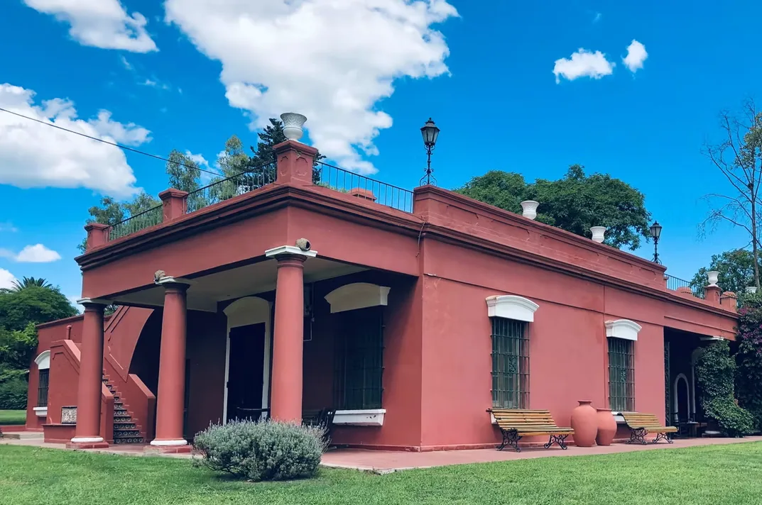A corner of the main house at Estancia La Loma under an open sky, with benches set along the wall