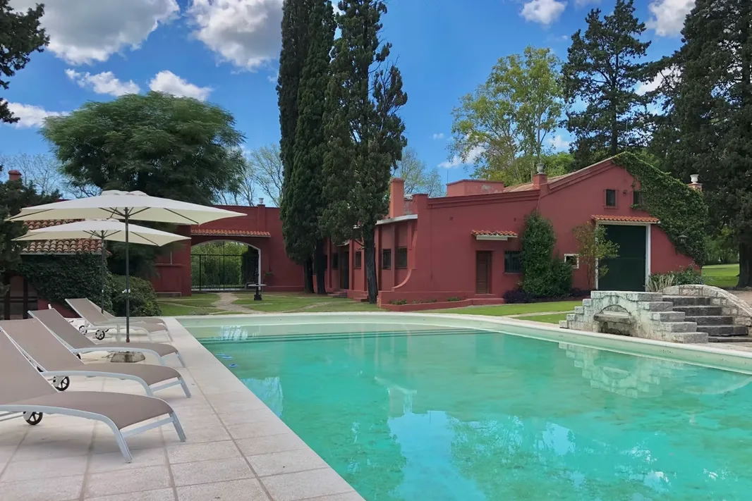 The pool at Estancia La Loma, with loungers and parasols along one side and the house behind it