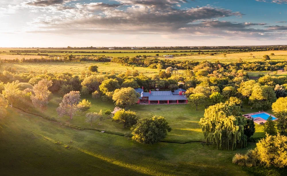 Río de Piedras vu du ciel au coucher du soleil : la maison dans le bois indigène, la piscine d'un côté et la plaine au-delà