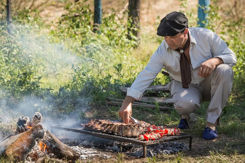 Ribs and skewers cooking on a grill over an open wood fire at Río de Piedras, tended by an asador