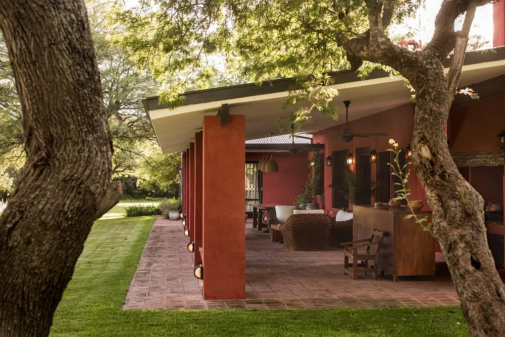 The covered gallery at Río de Piedras, furnished with wicker and looking onto the lawn