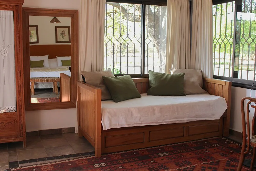 A bedroom at Río de Piedras with a wooden day bed under a barred window onto the garden