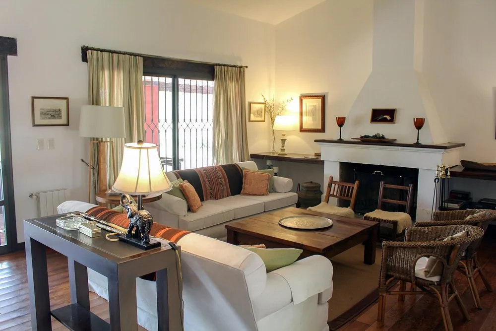 The sitting room at Río de Piedras, with sofas, wicker chairs and an open fireplace