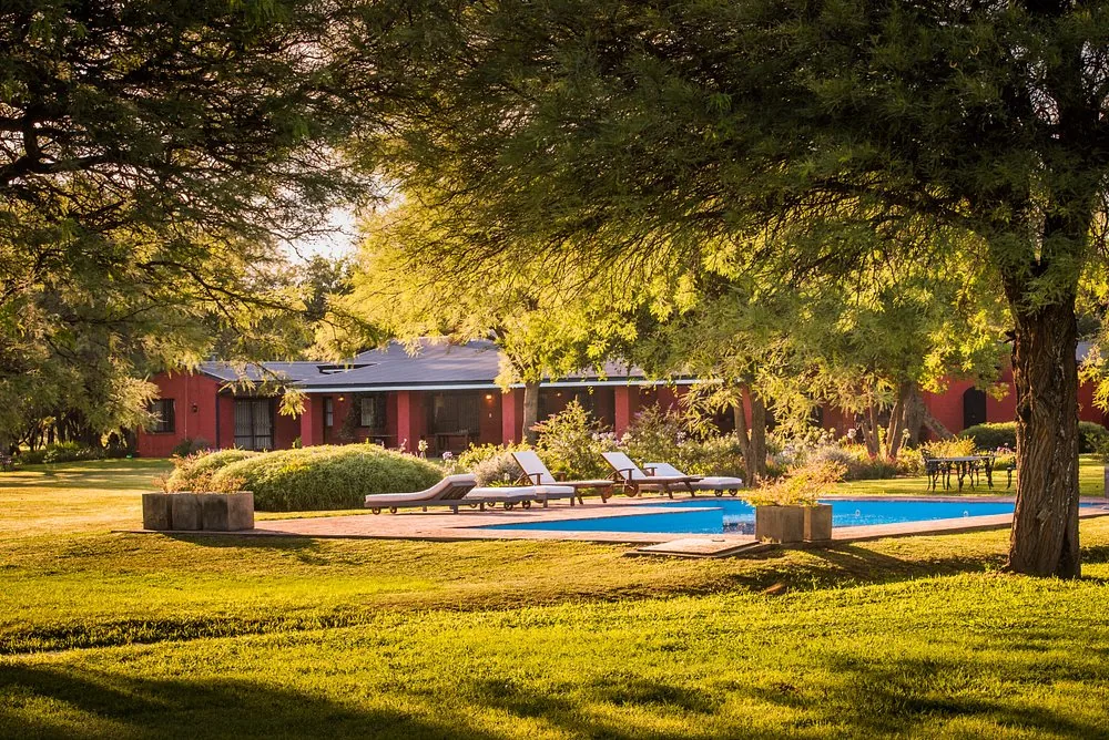 The pool at Río de Piedras, with loungers on the deck and the house behind the trees